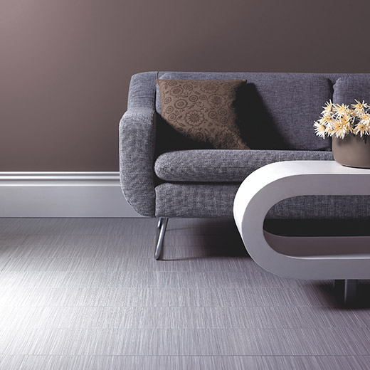 Image of a gray couch with a round coffee table on tile for the commercial flooring page